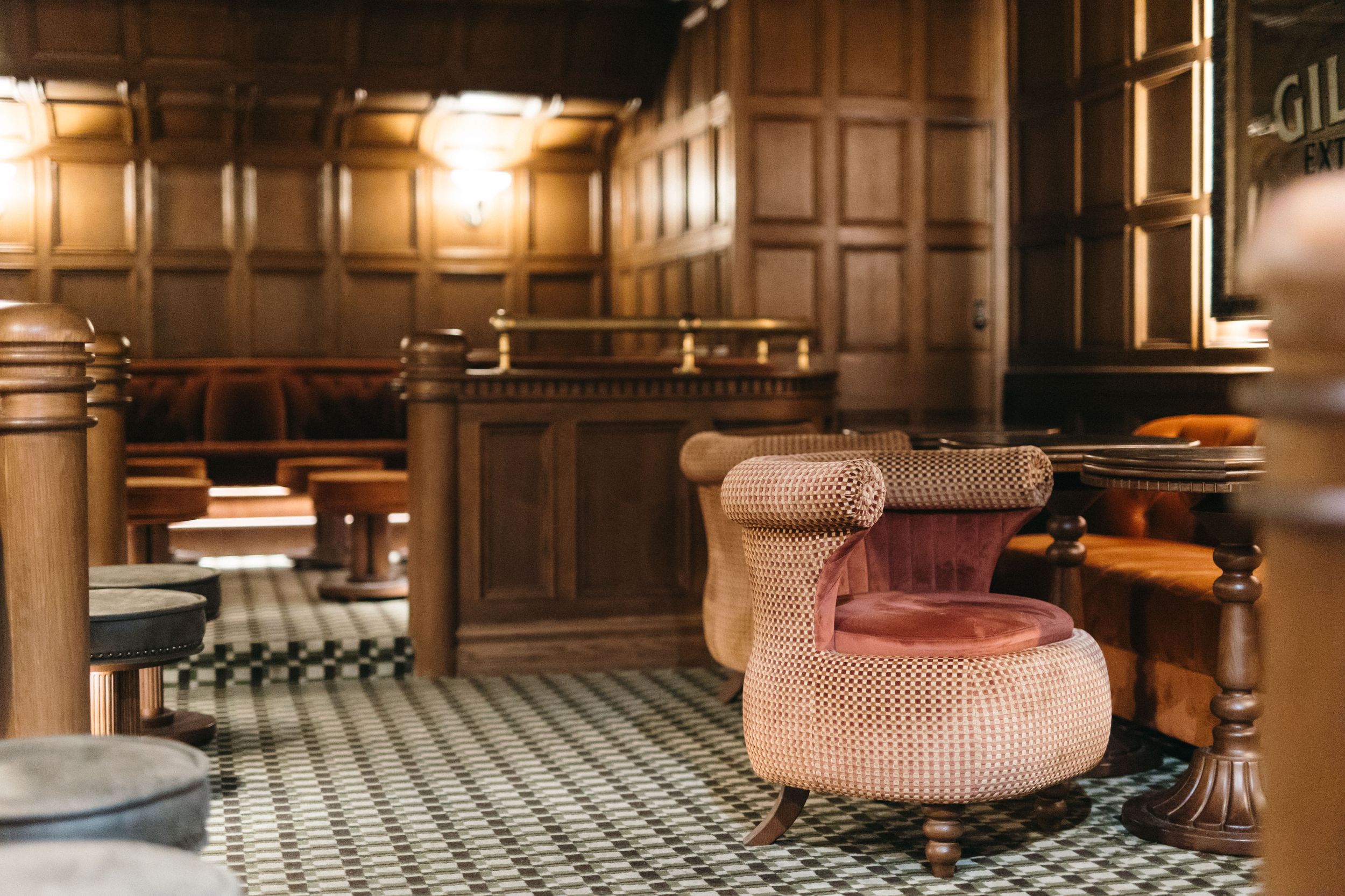Elegant vintage courtroom interior with wood paneling, pink velvet armchair, and checkered floor tiles.