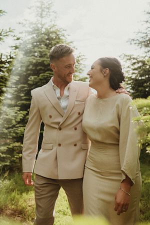 A couple in matching cream outfits share intimate moments during their outdoor wedding photoshoot.