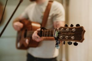 Close-up shots of acoustic guitar headstock and strings during a musical performance.