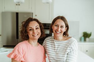 Two people sharing laughter in a bright modern kitchen setting.
