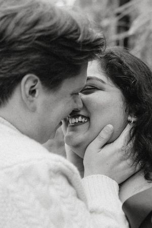 Black and white photo of a smiling couple sharing a tender romantic moment, foreheads touching.