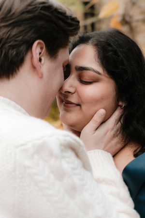 A tender moment as a couple leans in for a kiss, with a man in a white sweater gently cupping a woman's face.