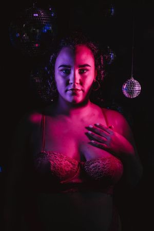 Studio portrait with dramatic red and blue lighting featuring disco ball and dark shadows in nightclub setting. boudoir photography