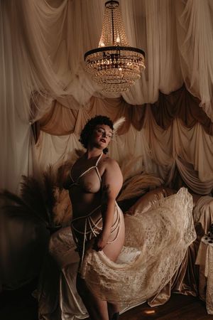 Artistic boudoir photo series with flowing fabric and crystal chandelier in warm tones creating romantic ambiance. boudoir photography in st