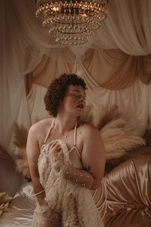 Vintage boudoir photo series featuring crystal chandeliers, pearls, and soft draped fabrics in warm sepia tones. boudoir photography in stud