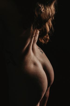 Artistic nude figure study showing a dark silhouette against black background in moody low key lighting. Boudoir Studio Photography
