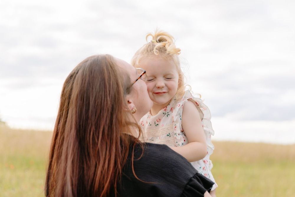 Tender moment shared between parent and child in a sunlit meadow.