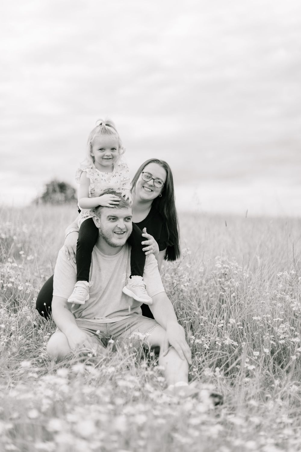 Black and white portrait of a happy family sitting together in a meadow.