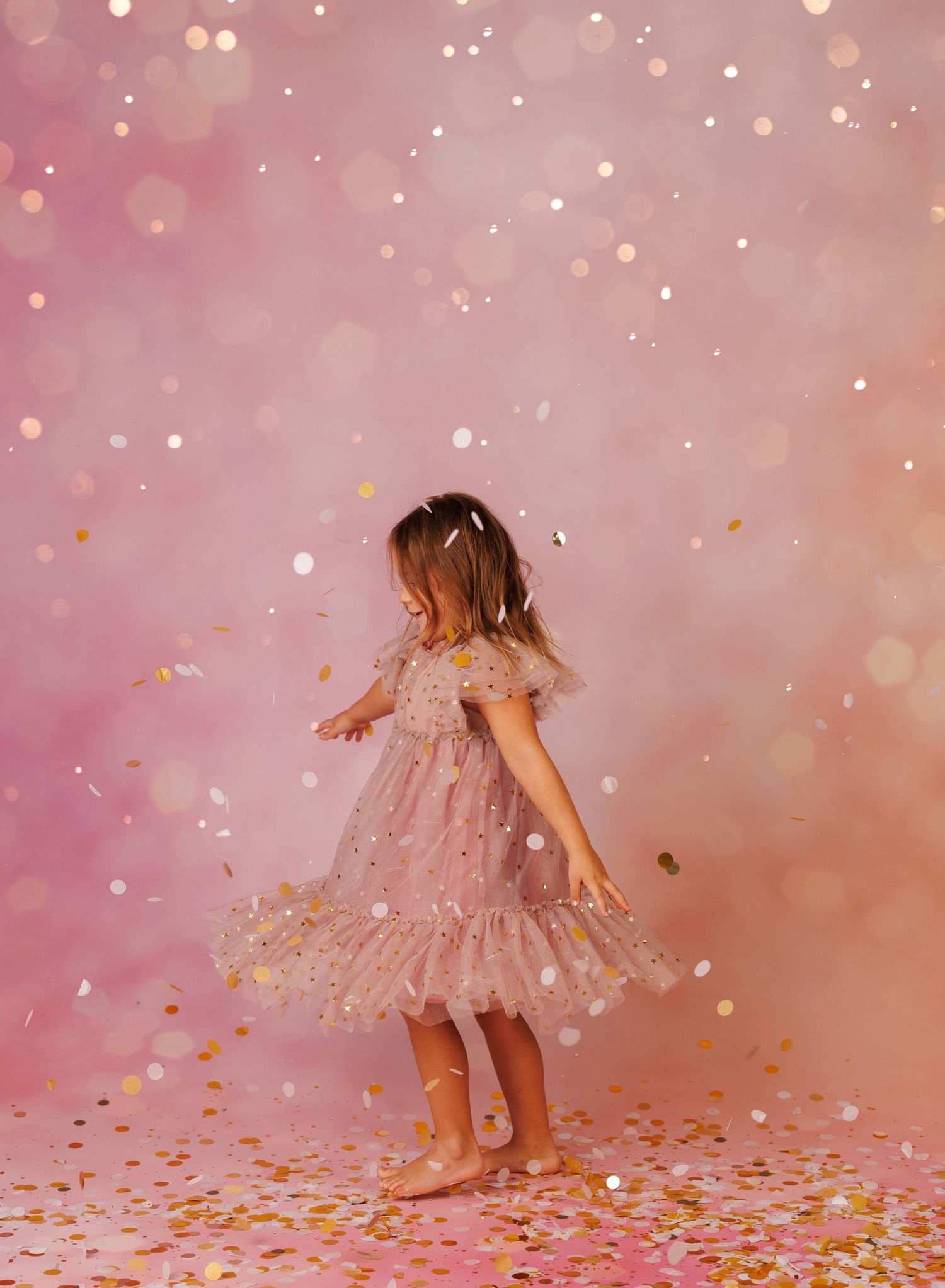 A dreamy sequence of someone twirling in a pink tulle dress against a sparkly rose gold background with falling confetti.