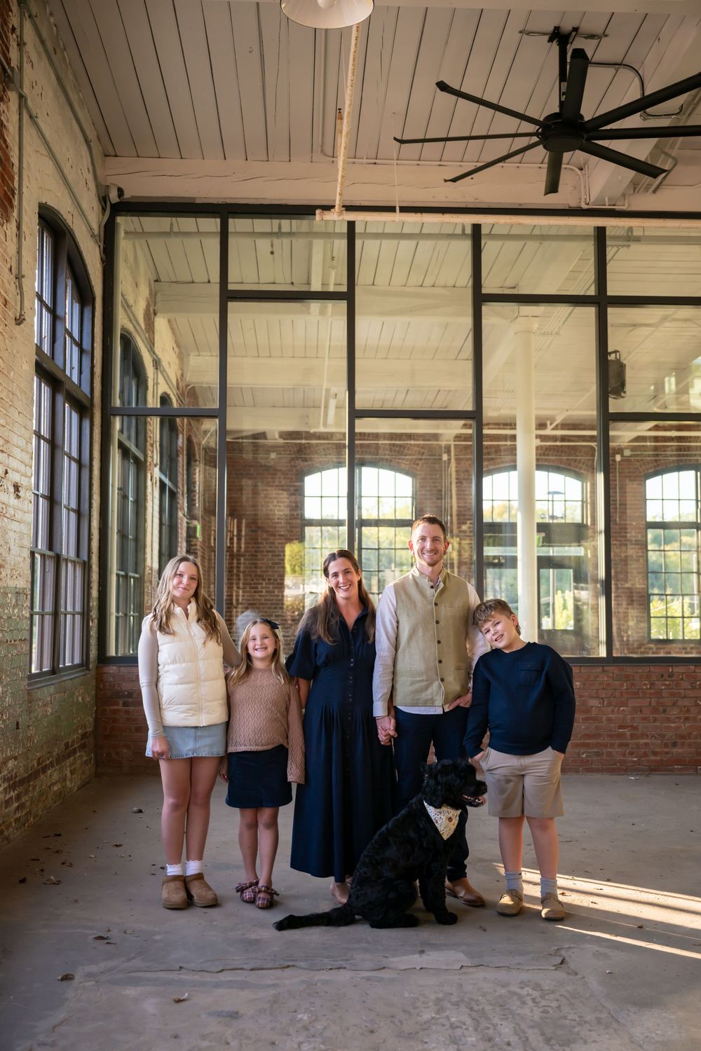 Group photo session in an empty industrial loft space with exposed brick walls and large windows letting in natural light.