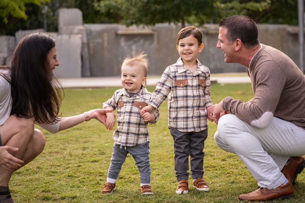 Family enjoying quality time together while playing and running on grass in a park on a sunny day.