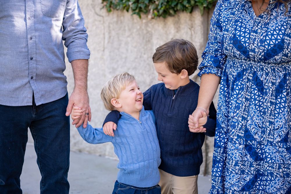 A family wearing coordinated blue and denim outfits poses together outdoors for a casual portrait session.