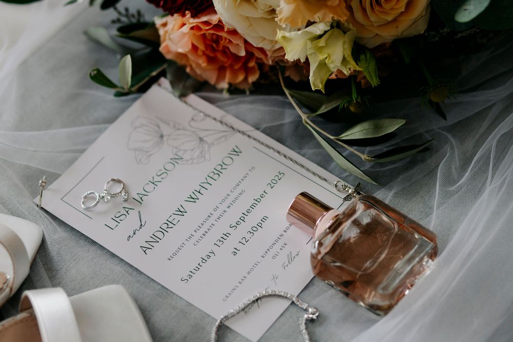 Elegant wedding invitation suite displayed with vintage roses and delicate ribbons in soft peach and cream tones.
