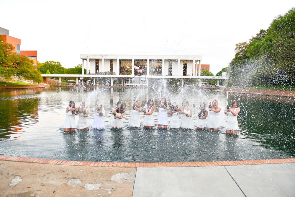 A modern fountain sprays water in front of a contemporary white building structure.