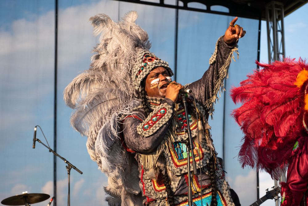 Performer in traditional costume with feathers dances energetically on stage.