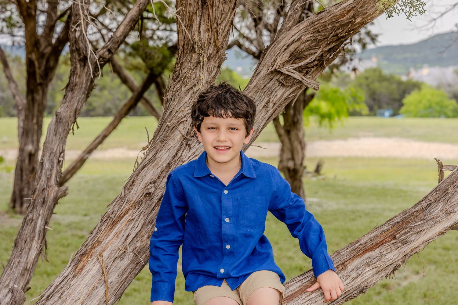 Two children sitting among vibrant bluebonnets near a lake.