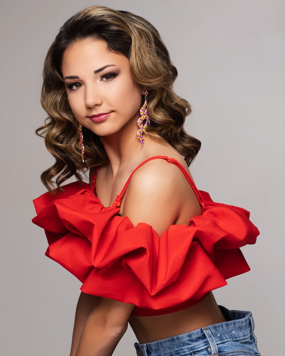 Studio portraits of a figure in wavy brown hair and red ruffled top with denim, shown from different angles.