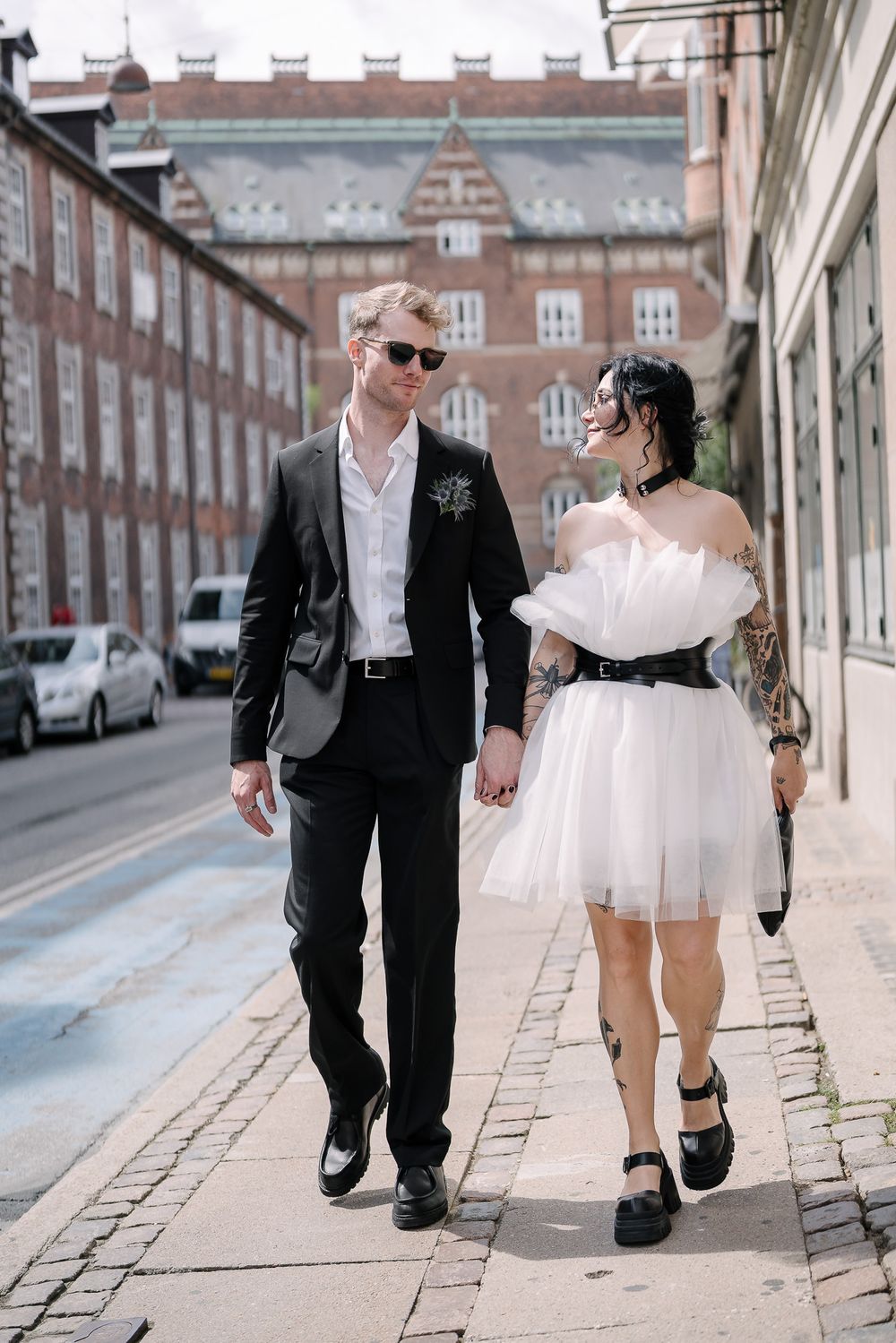 A couple is walking hand in hand down a city sidewalk after their destination wedding ceremony in Copenhagen