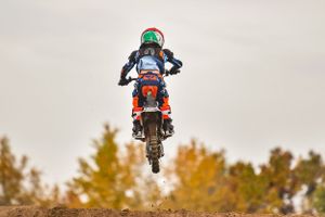 Motocross riders performing jumps against fall foliage background.