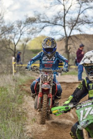 Dirt bike rider navigates challenging terrain on motocross track during race.