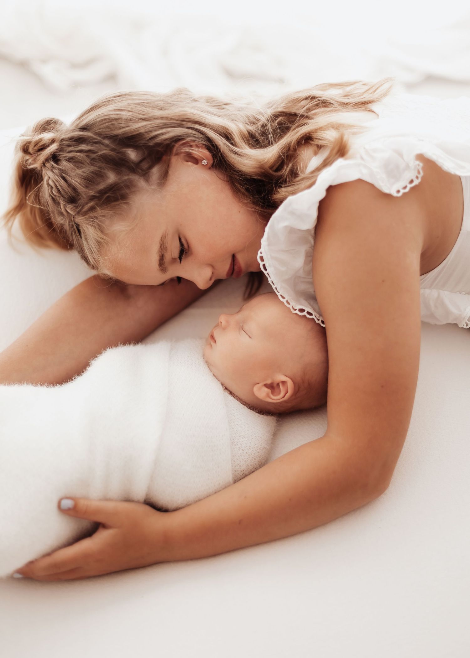 Adorable baby with bright blue eyes lying on white background.