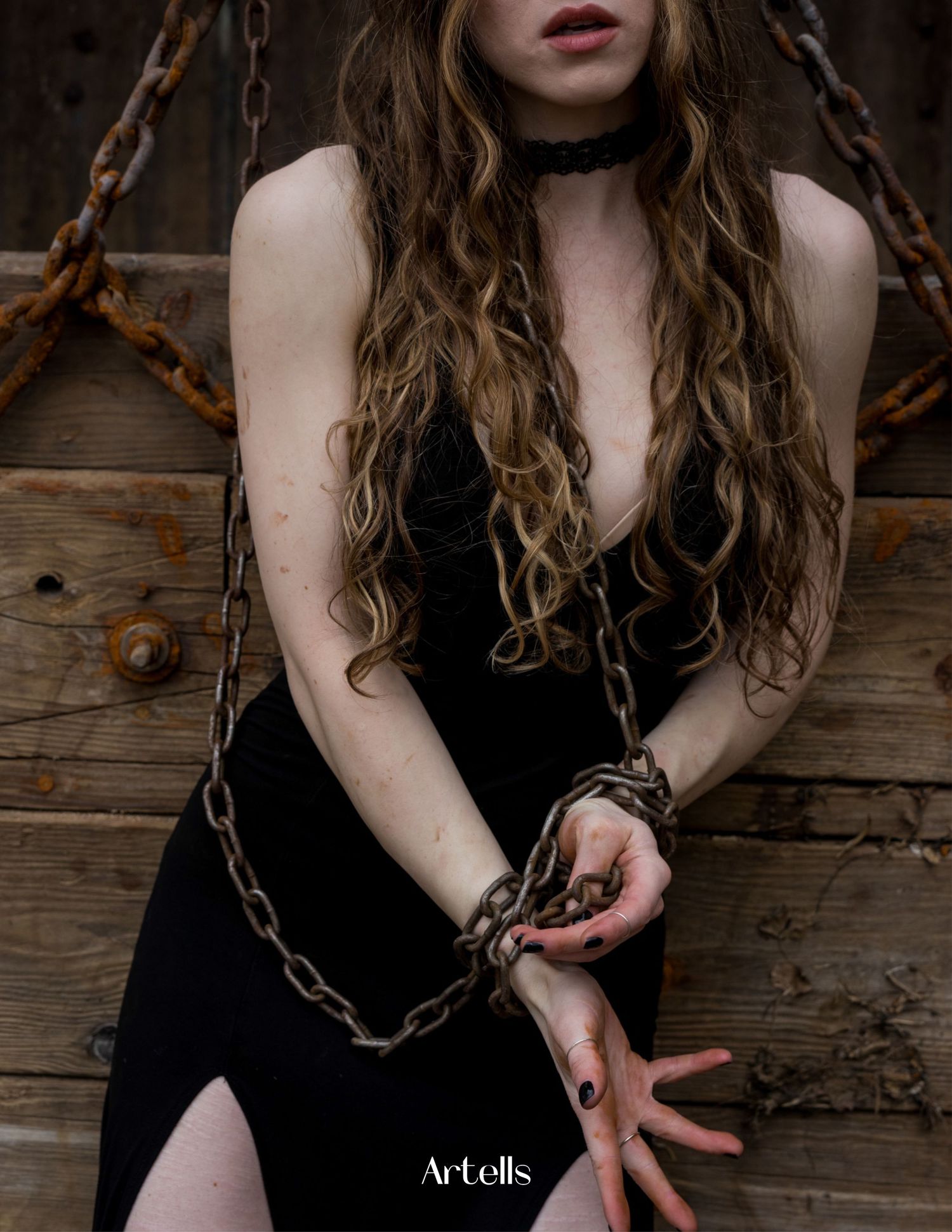 Thought provoking image of woman's pale hands bound by rusty metal chains against dark background with magazine title Artell's