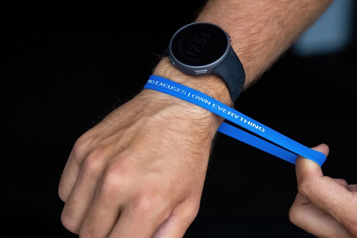 Close-up of a wrist wearing a smartwatch and a blue wristband with text at an event.
