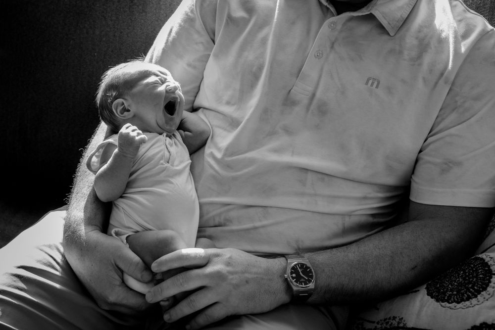 Moody black and white image capturing father and newborn. Lifestyle newborn photoshoot in Las Vegas. Lifestyle Newborn photography Las Vegas