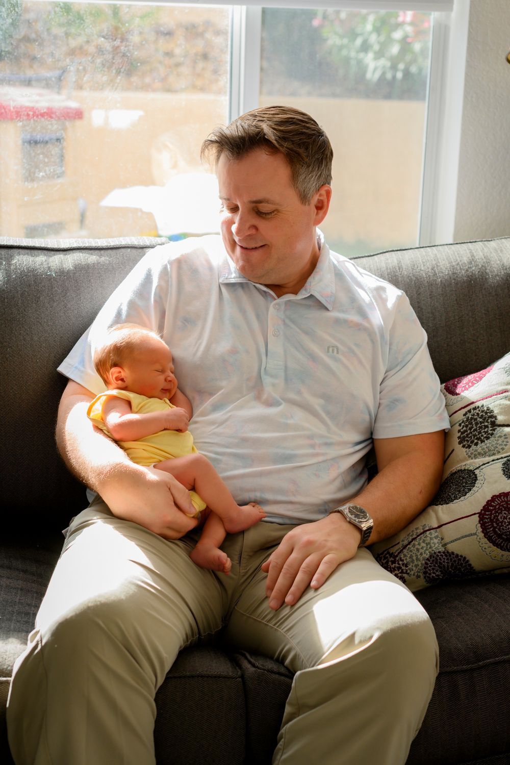 A tender moment as a father cradles a newborn baby. Lifestyle newborn photoshoot in Las Vegas. Lifestyle Newborn photography in Las Vegas.