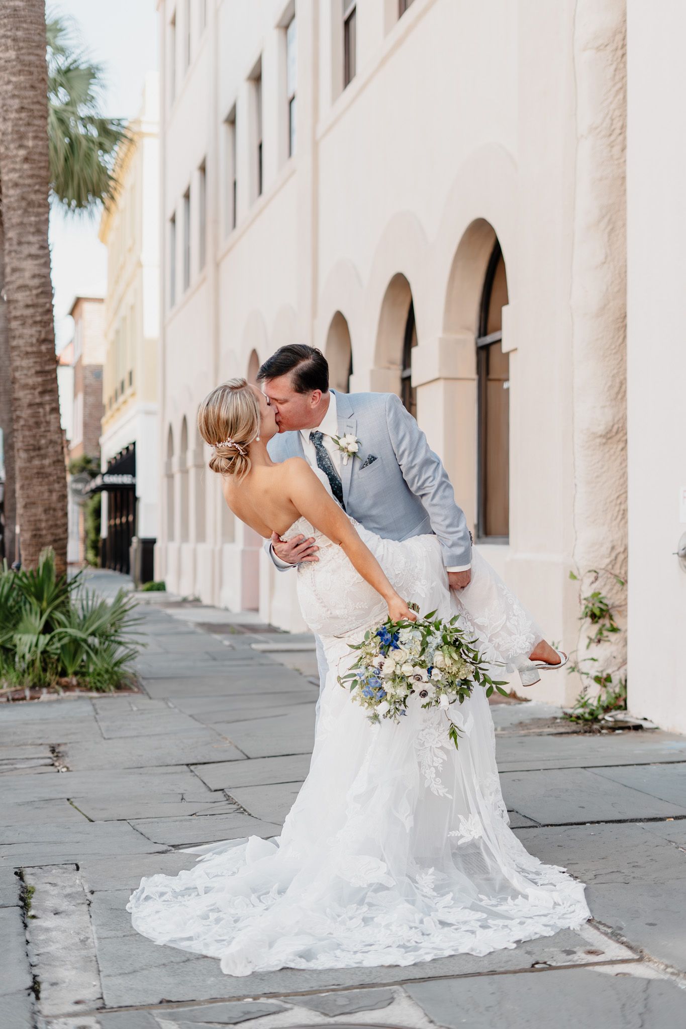 A romantic wedding moment captured on a historic Charleston street with classic architecture.