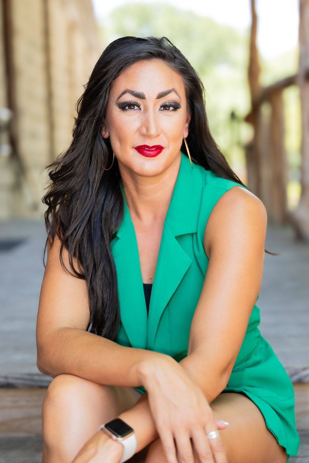 Professional portrait photo featuring a vibrant green sleeveless blazer, bold red lipstick and long dark hair.