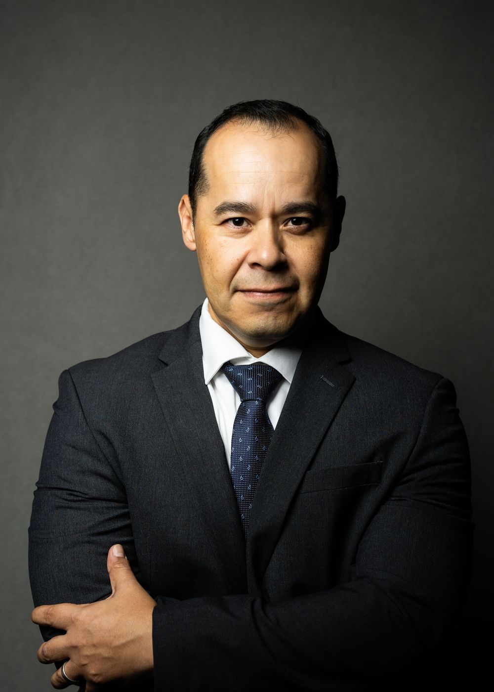Professional portrait series showing a man in a dark business suit against a gray background in various poses.