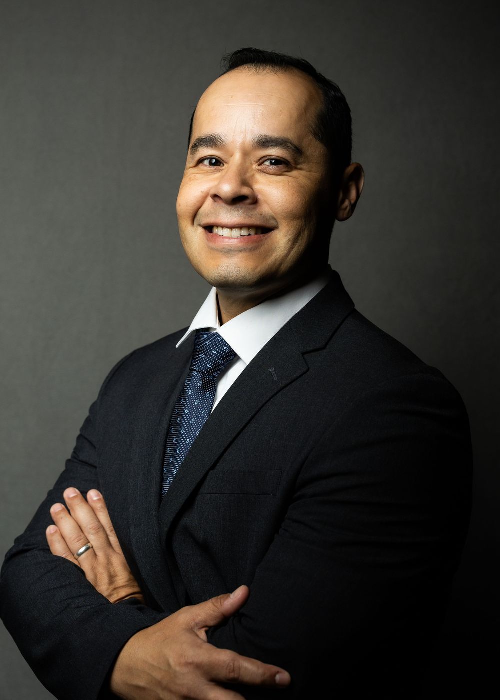 Professional studio portraits show person in black suit and tie against dark background with various poses and expressions.