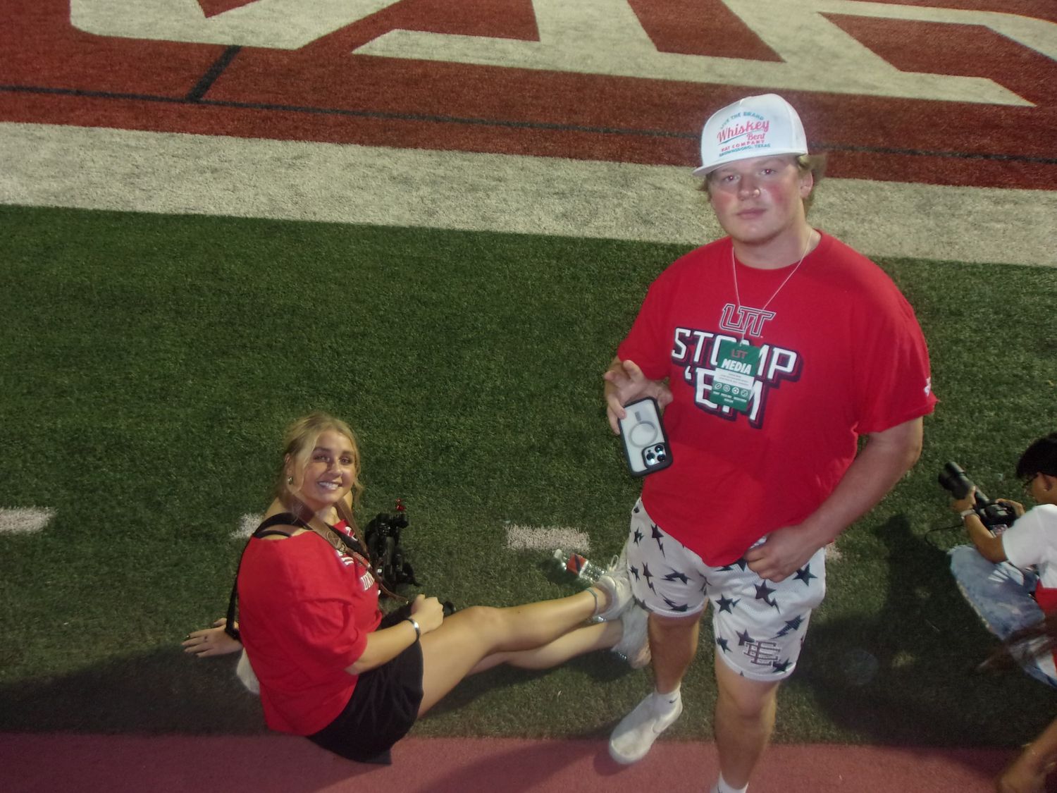 People relaxing on a sports field with red markings wearing casual attire.