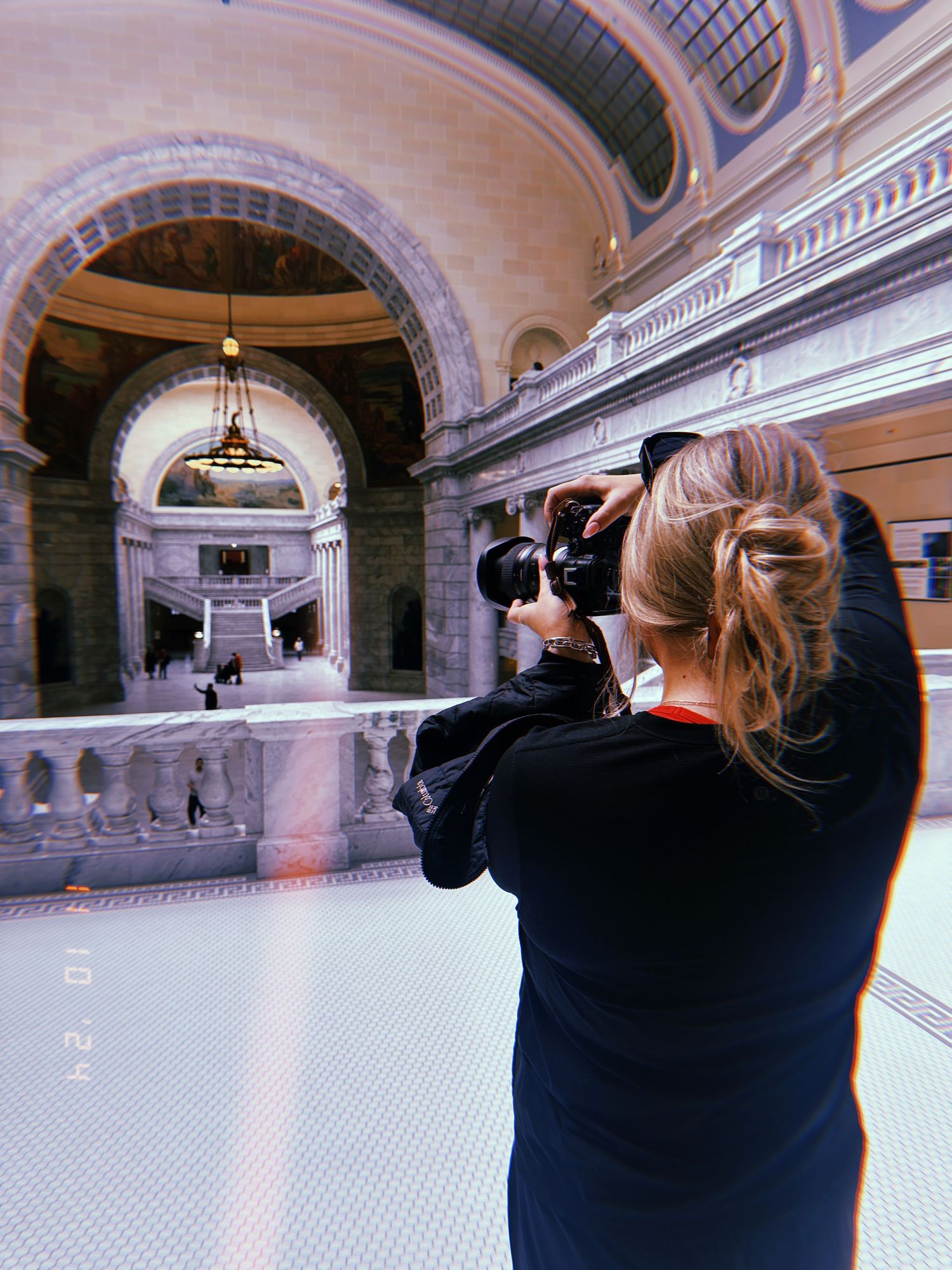 Photographer capturing photos inside an ornate historic building with arched architecture.