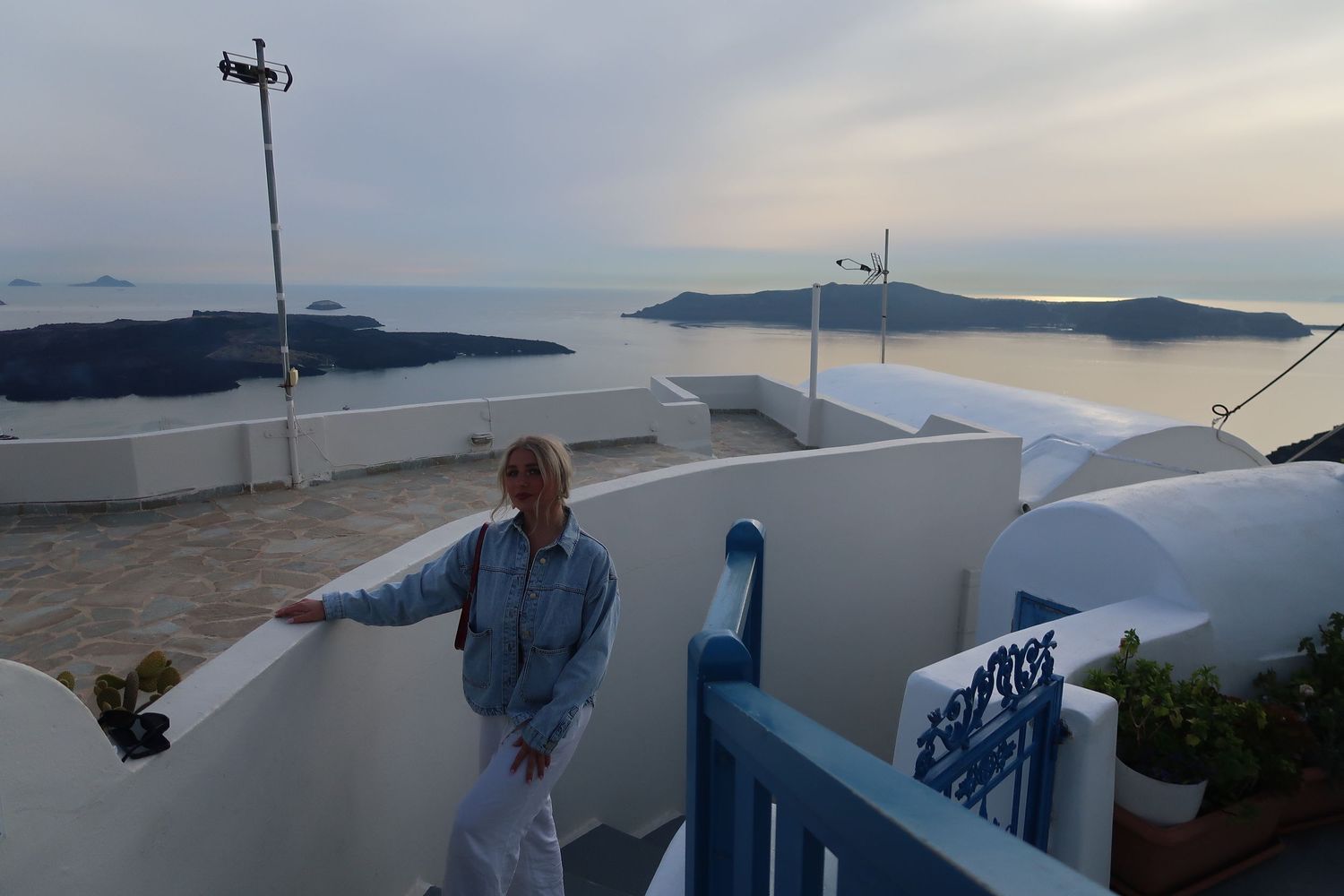 A scenic white balcony view overlooking the Santorini caldera at dusk.