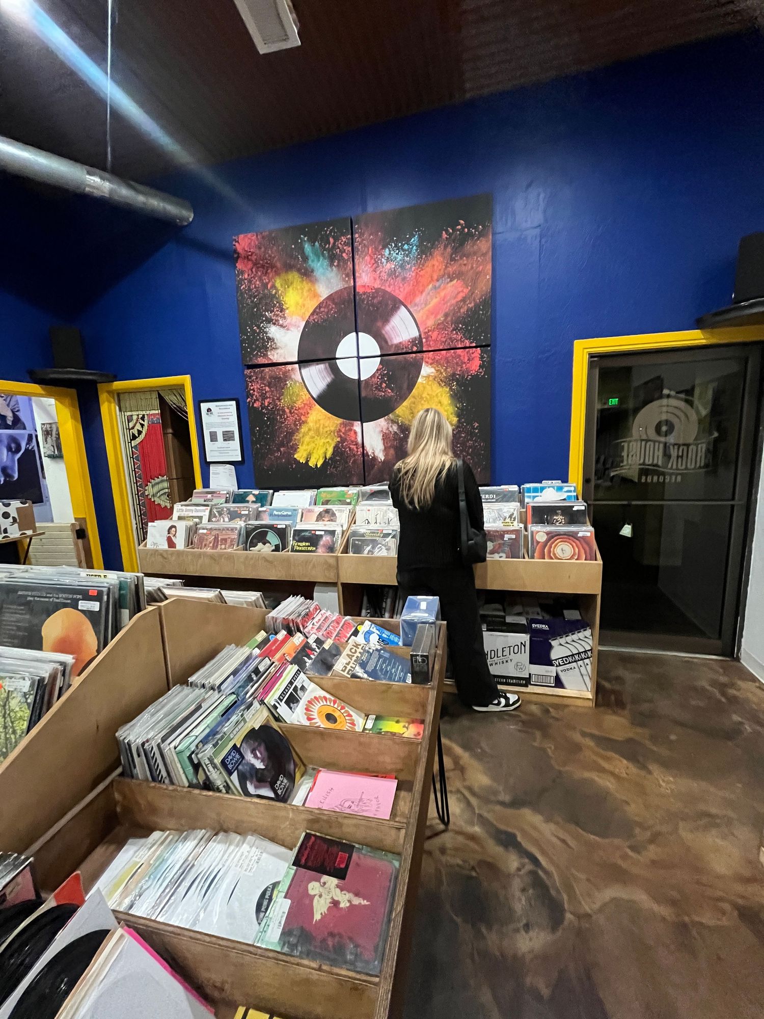 Record store interior with vinyl bins and colorful wall art featuring a cosmic record design.