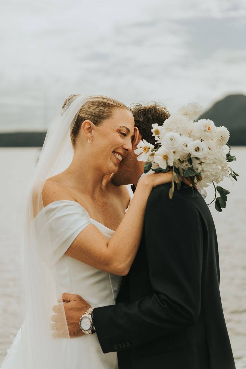 Newlyweds embrace in a series of romantic poses by the waterfront during their wedding day.