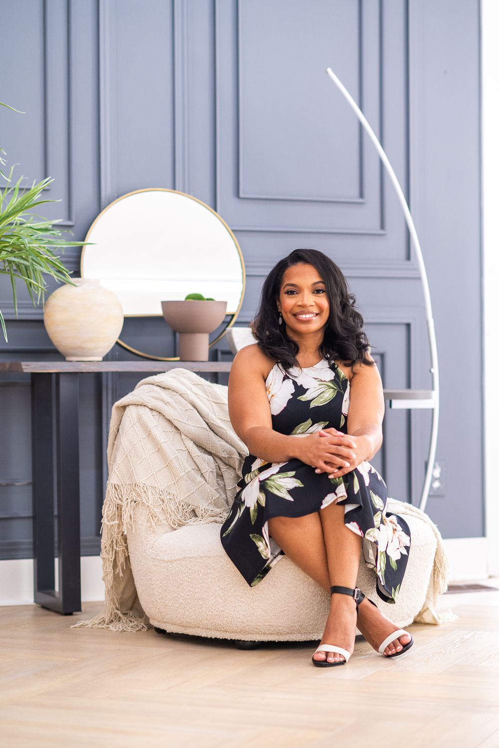A woman is seated on a brown ottoman in a boho-themed office.