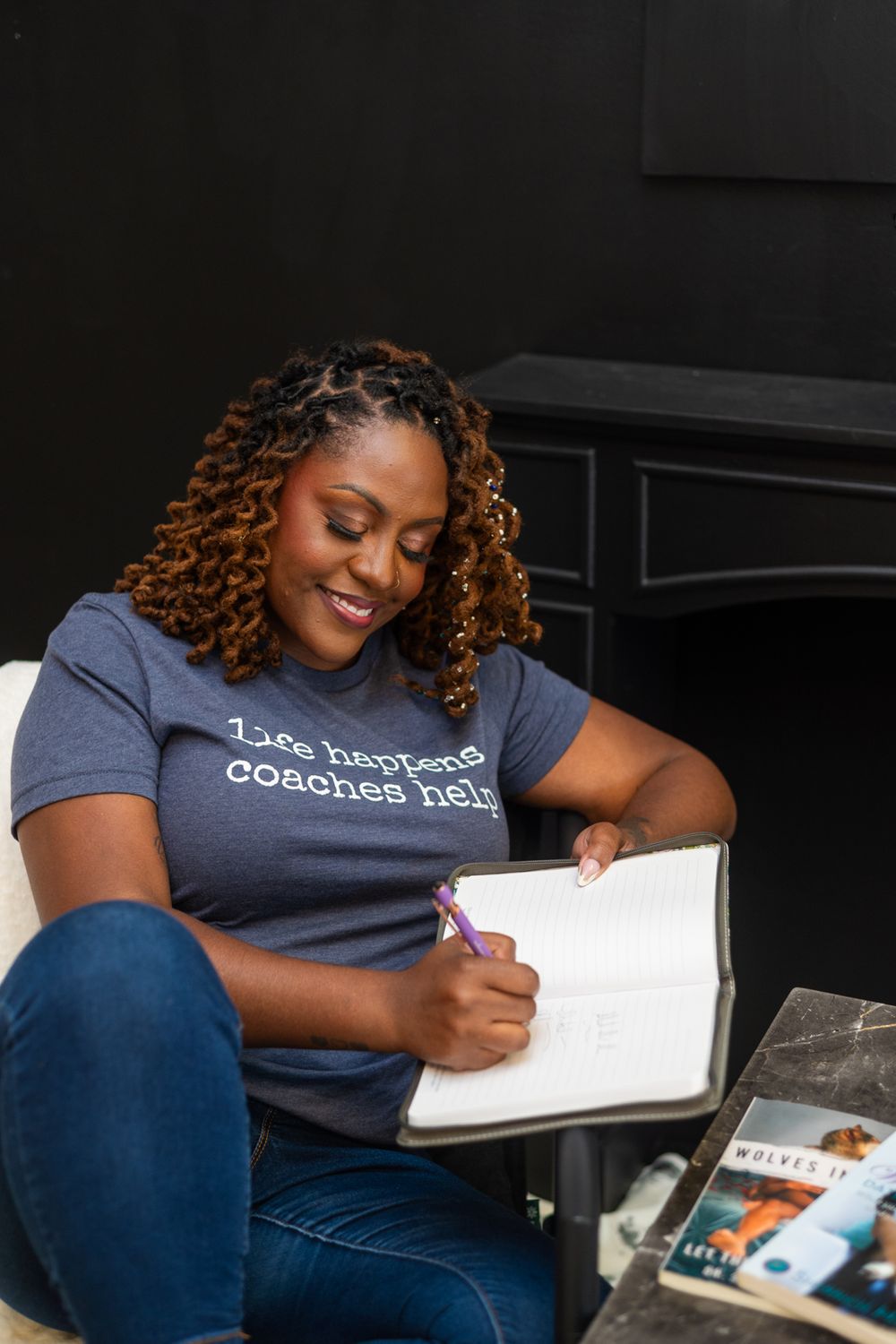 A life coach smiles while looking down and writing in her notebook.
