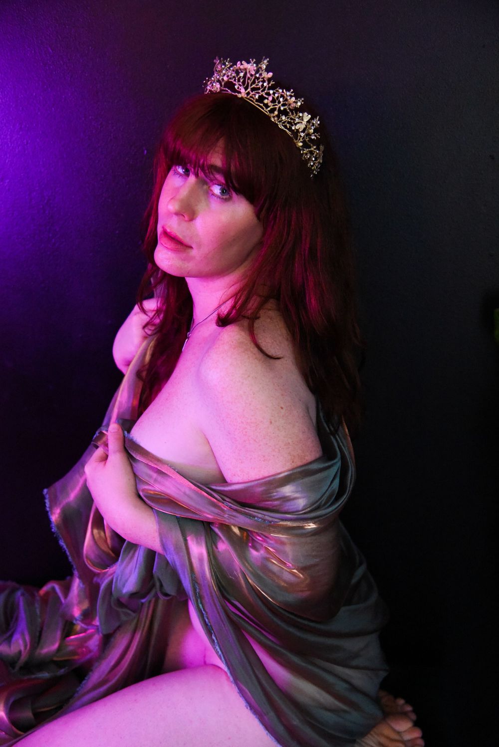 Artistic portrait series with purple lighting shows a figure in flowing fabric striking dramatic poses against dark background.