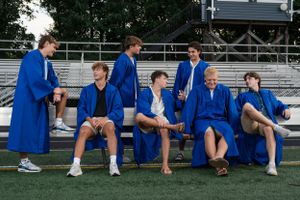 Athletes in blue uniforms sit on metal bleachers during a sports event.