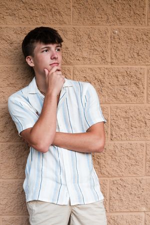 Casual poses against a textured beige brick wall background.