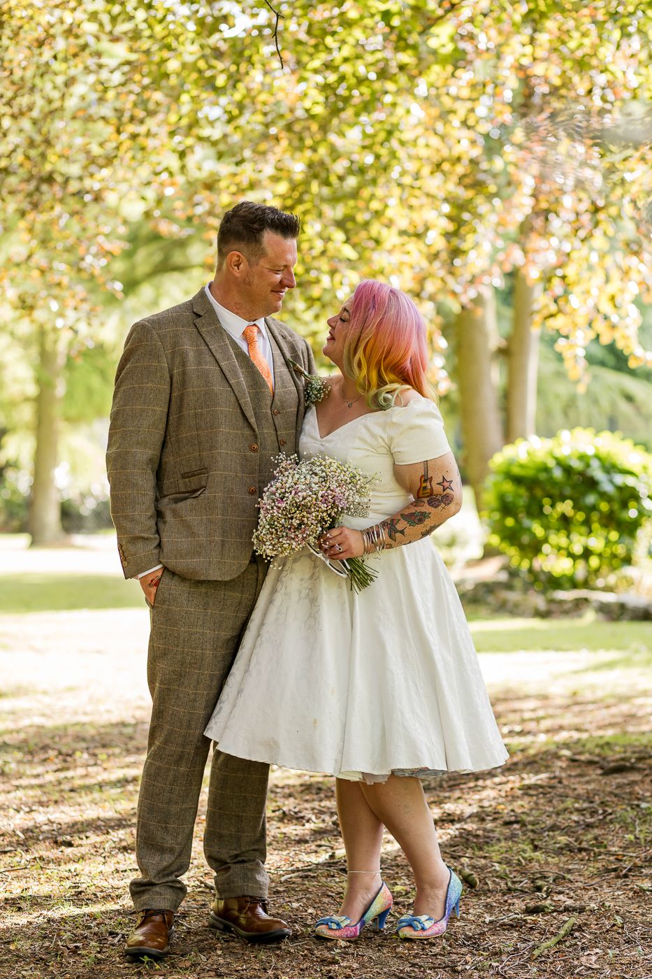 Romantic autumn wedding photos taken in a wooded setting with golden sunlight filtering through trees.