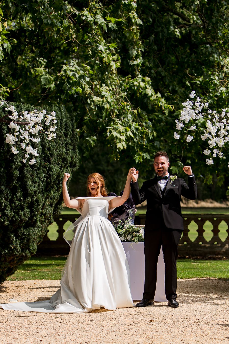 Celebratory moment in a garden setting with white floral arrangements.