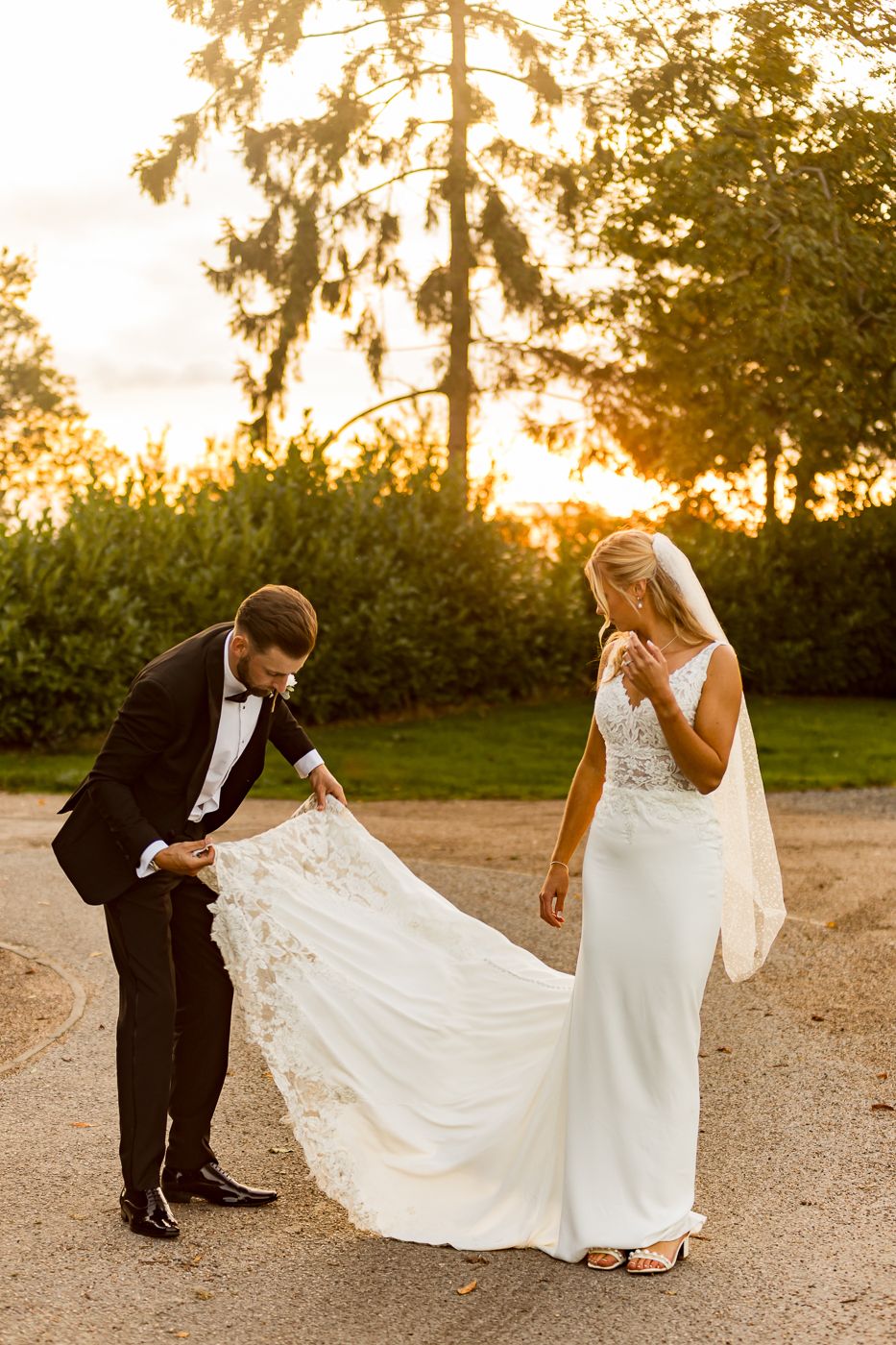 A romantic sunset wedding photoshoot with a couple on a dirt path surrounded by golden light.