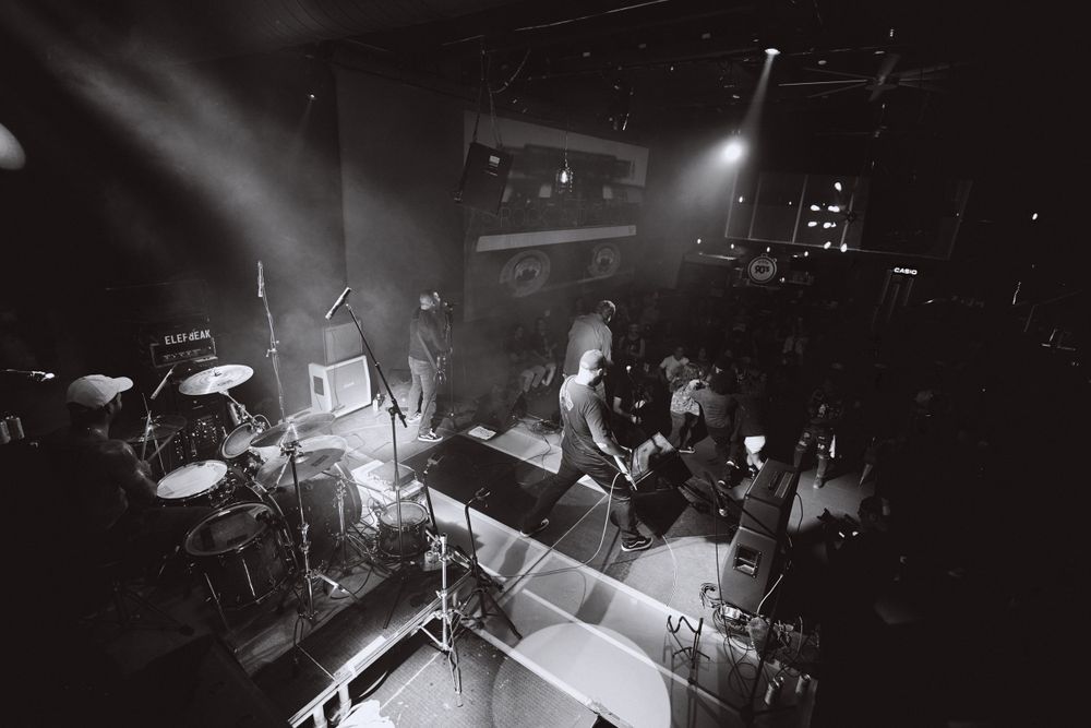 High-angle black and white shot of band members performing on illuminated stage.