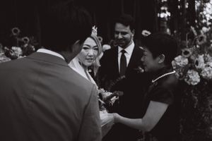 A black and white candid moment during a wedding ceremony with flowers in the background.