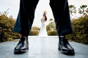 Creative wedding photo framing bride between groom's legs on path.