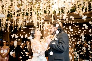 Newlyweds celebrate under hanging lights as confetti falls around them.